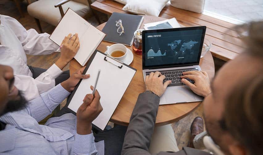 Close-up of EB5 analysts discussing investment data and annual statistics on a laptop, representing transparency and financial reporting in EB5 projects.