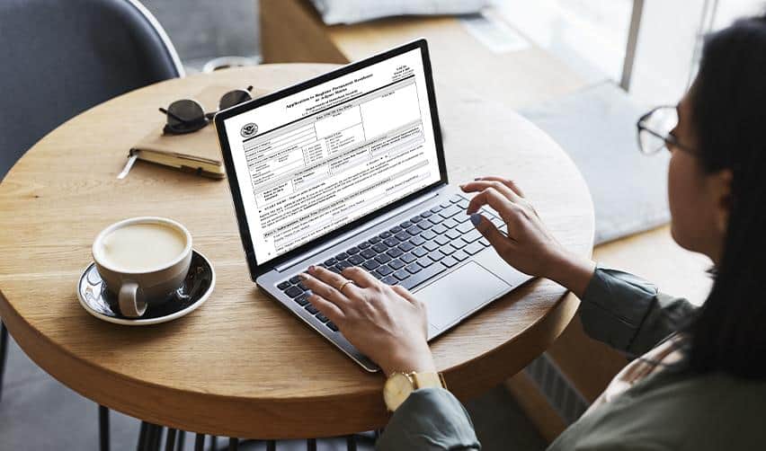 Person reviewing a USCIS immigration form on a laptop, illustrating how EB5 investors research Adjustment of Status and concurrent filing requirements while in the United States.