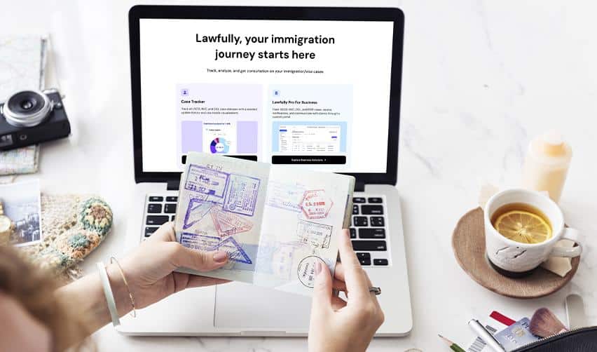 An EB5 investor holding a passport in front of a laptop displaying an immigration tracking platform, symbolizing monitoring EB5 immigration progress and visa status online.