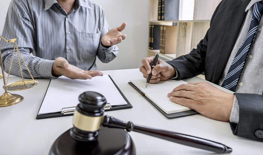 An attorney meeting with a client at a desk with a gavel and legal documents, representing legal consultation regarding employment-based immigration and the Gold Card lawsuit.